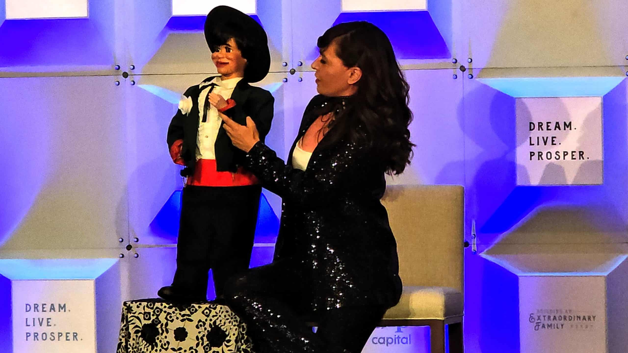 Ventriloquist performing on stage with a puppet during a live event
