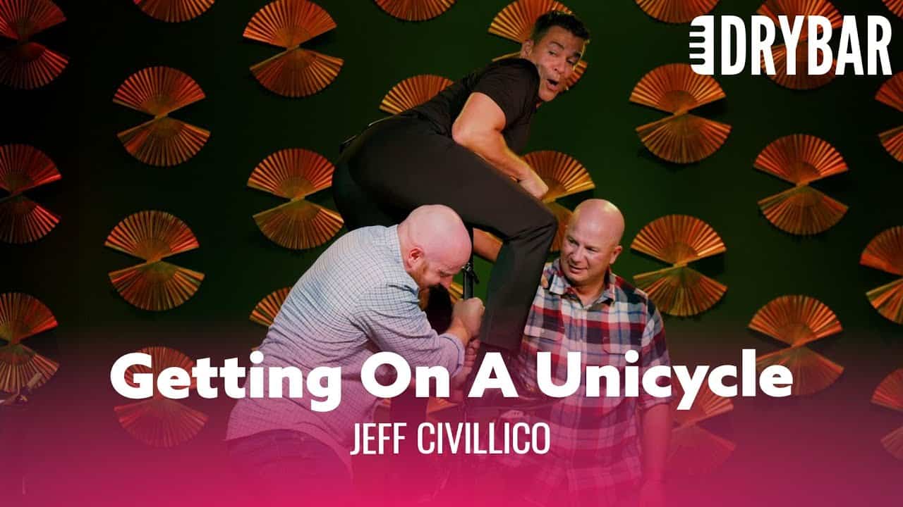 Jeff Civillico’s Interactive Comedy Performance – Unicycle Act Jeff Civillico balancing on a unicycle with audience members assisting him, showcasing his interactive comedy performance